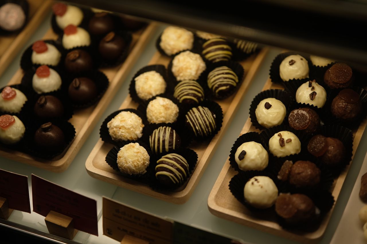 An appetizing assortment of various chocolate truffles on wooden trays under warm lighting.